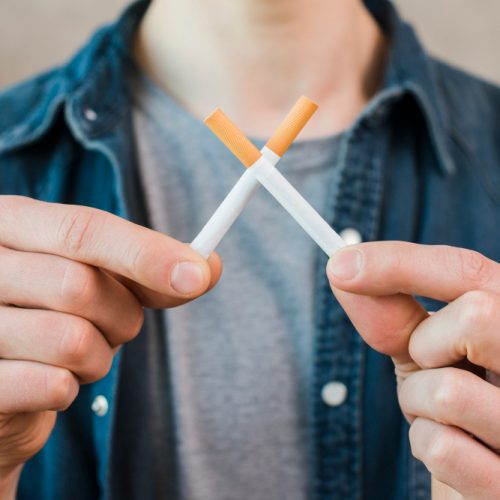 man-s-hand-holding-crossed-cigarettes man-s-hand-holding-crossed-cigarettes